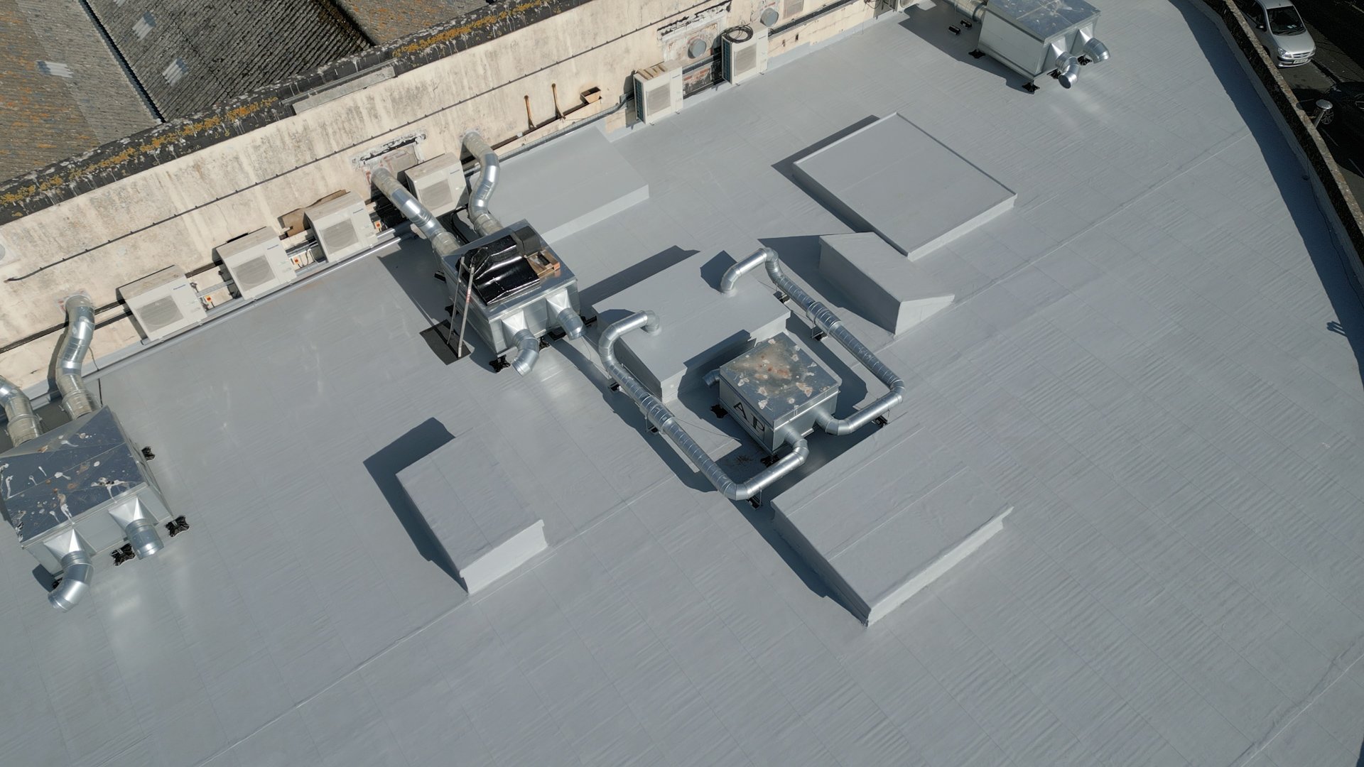 Aerial view of a commercial flat roof finished with a seamless grey GacoFlex overlay
