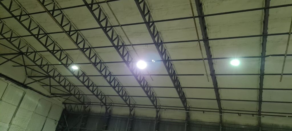 Finished spray foam across the roof and trusses of a steel-framed hangar.