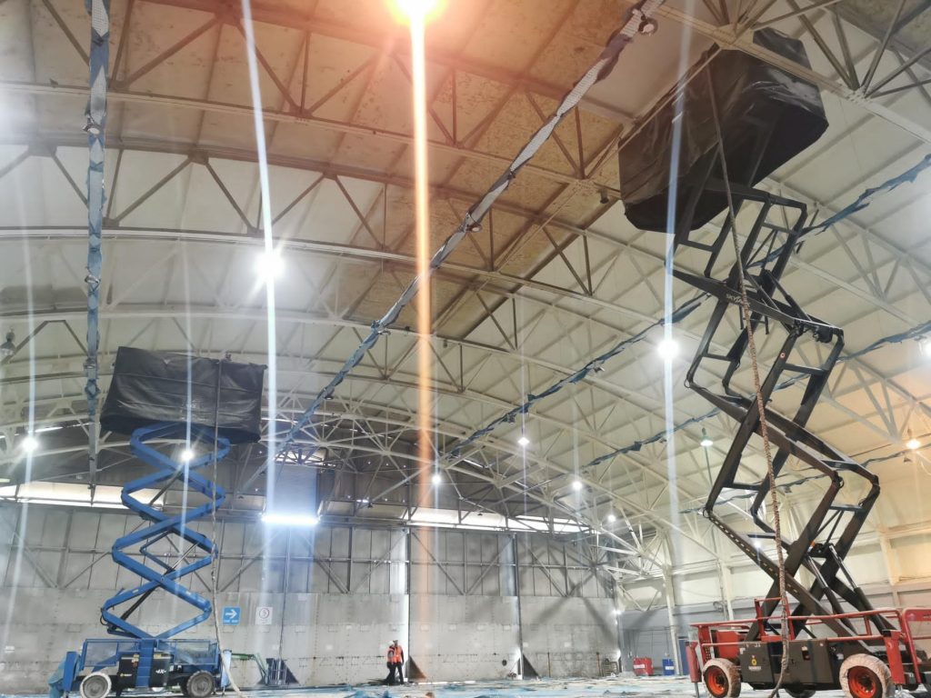 Scissor lifts set up for spray foam application inside a steel hangar.
