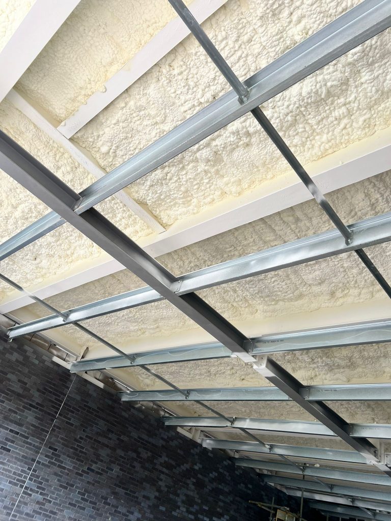 Completed spray foam soffit insulation between galvanised steel framing members.
