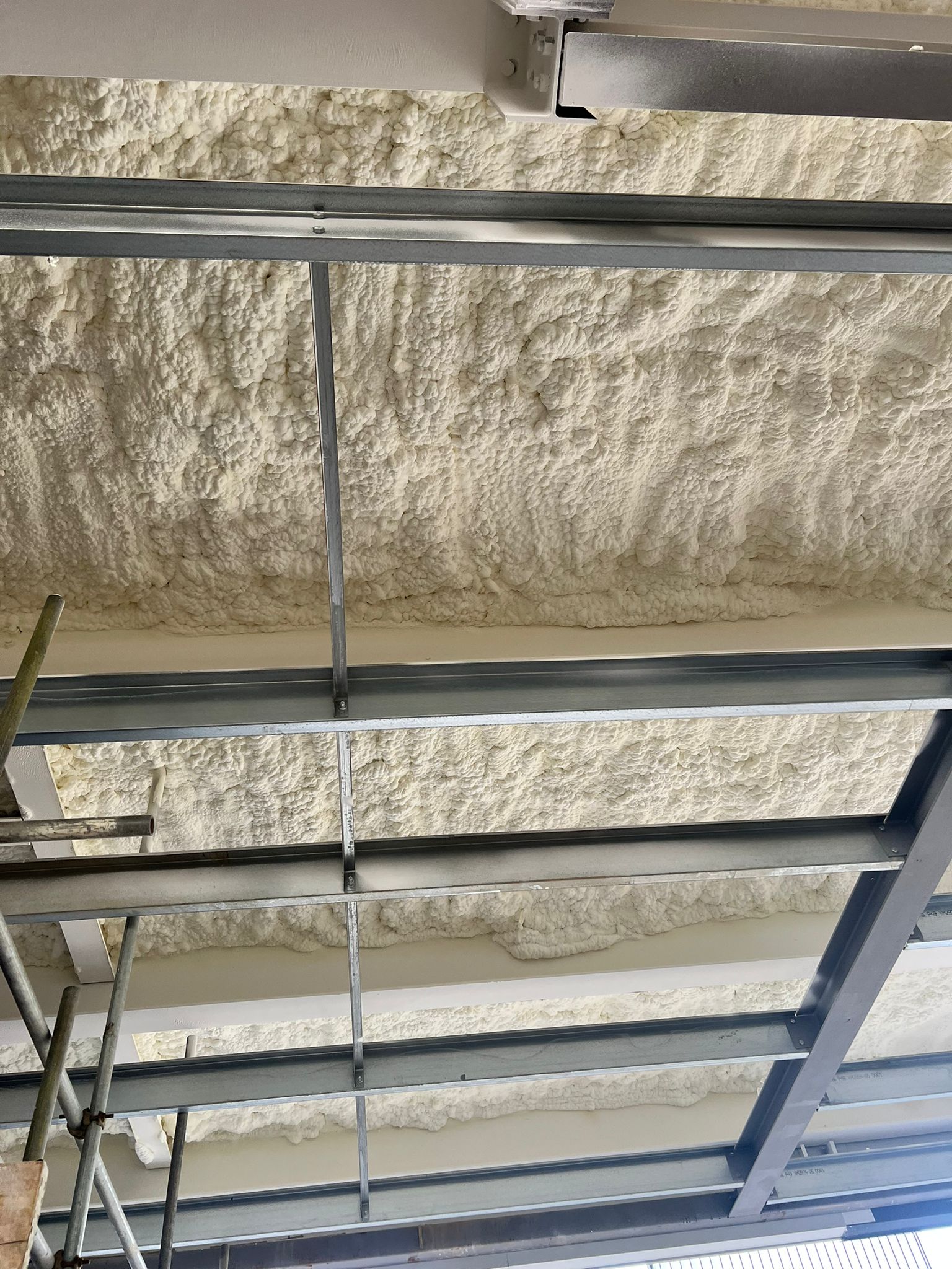Spray foam insulation between steel beams on multi-storey car park metal deck