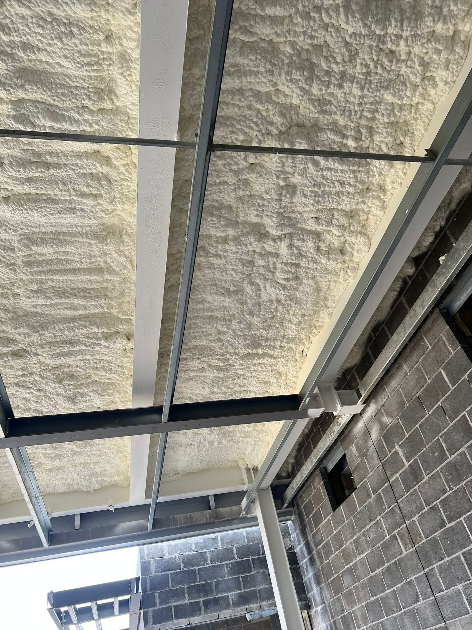 Corrugated metal industrial roof underside with closed-cell spray foam application