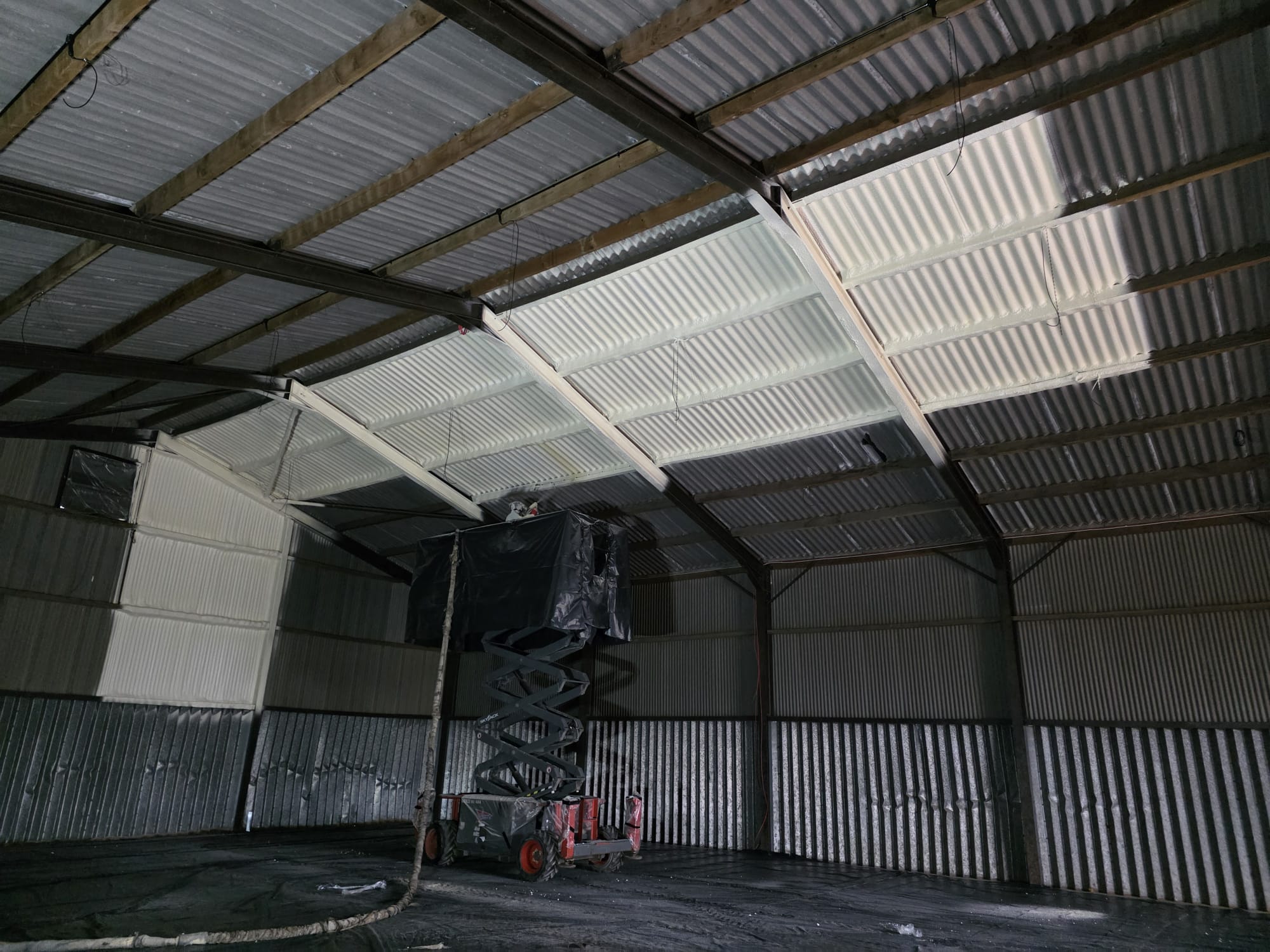 Operative spraying Nexseal LE closed-cell foam to the underside of an asbestos cement roof