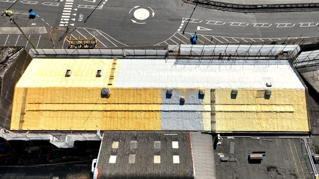 Roof part-way through: sprayed foam sections alongside the finished white coating at SAICA, Warrenpoint.